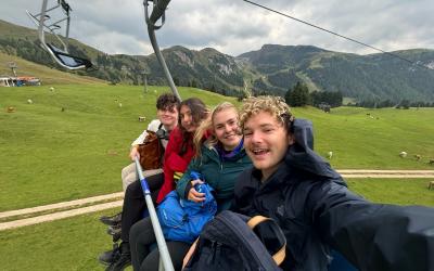 Four college students sitting on a skylift in the Dolomite Mountains in Italy. 