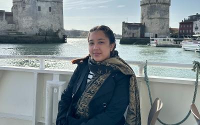 Person sitting on a boat with the historic Belem Tower in the background on a sunny day.